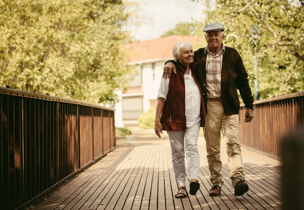 An elderly couple walking on a bridge.